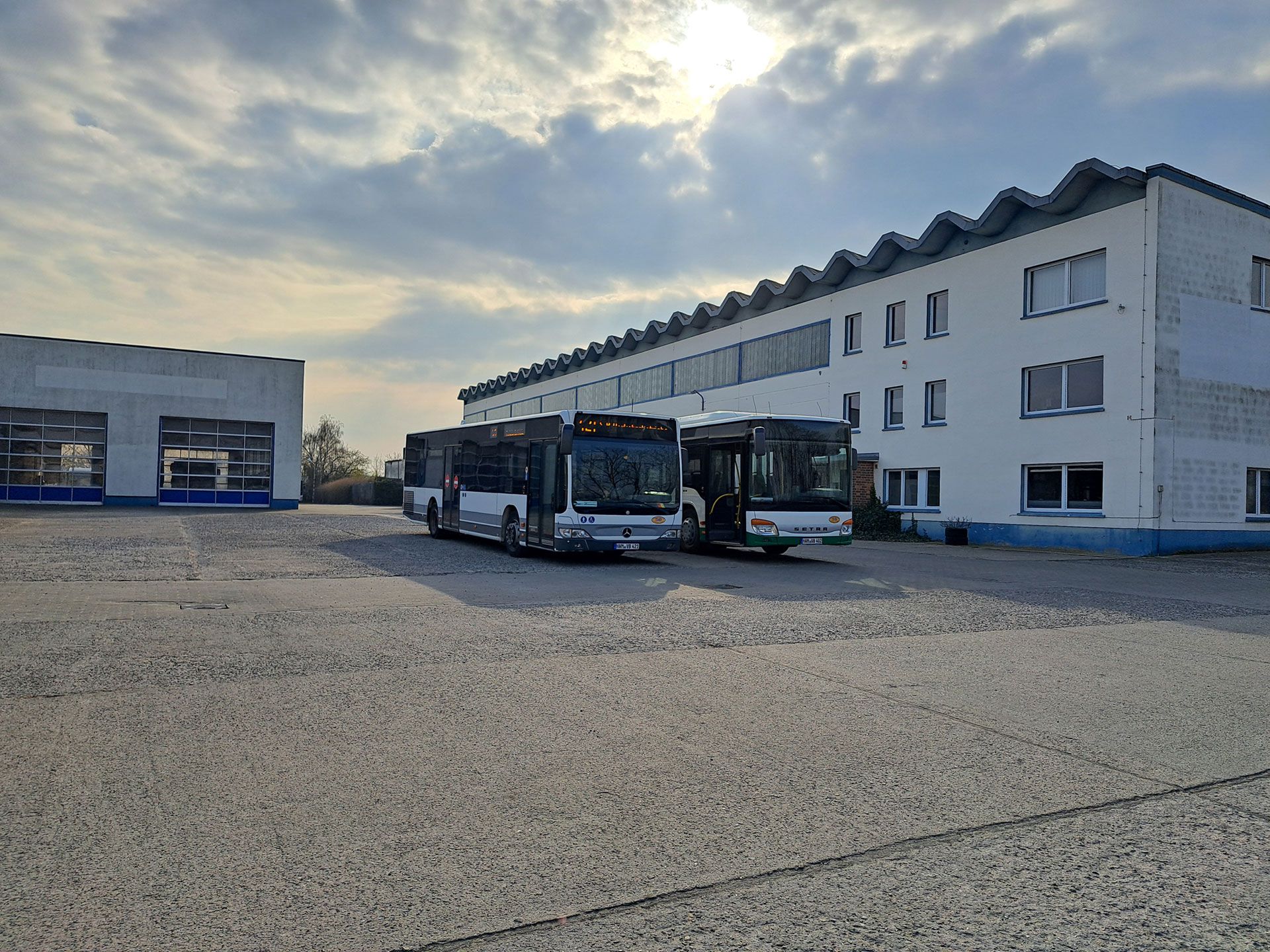 Zwei komfortable Busse stehen vor einem Gebäude, ideal für entspannte Reisen.