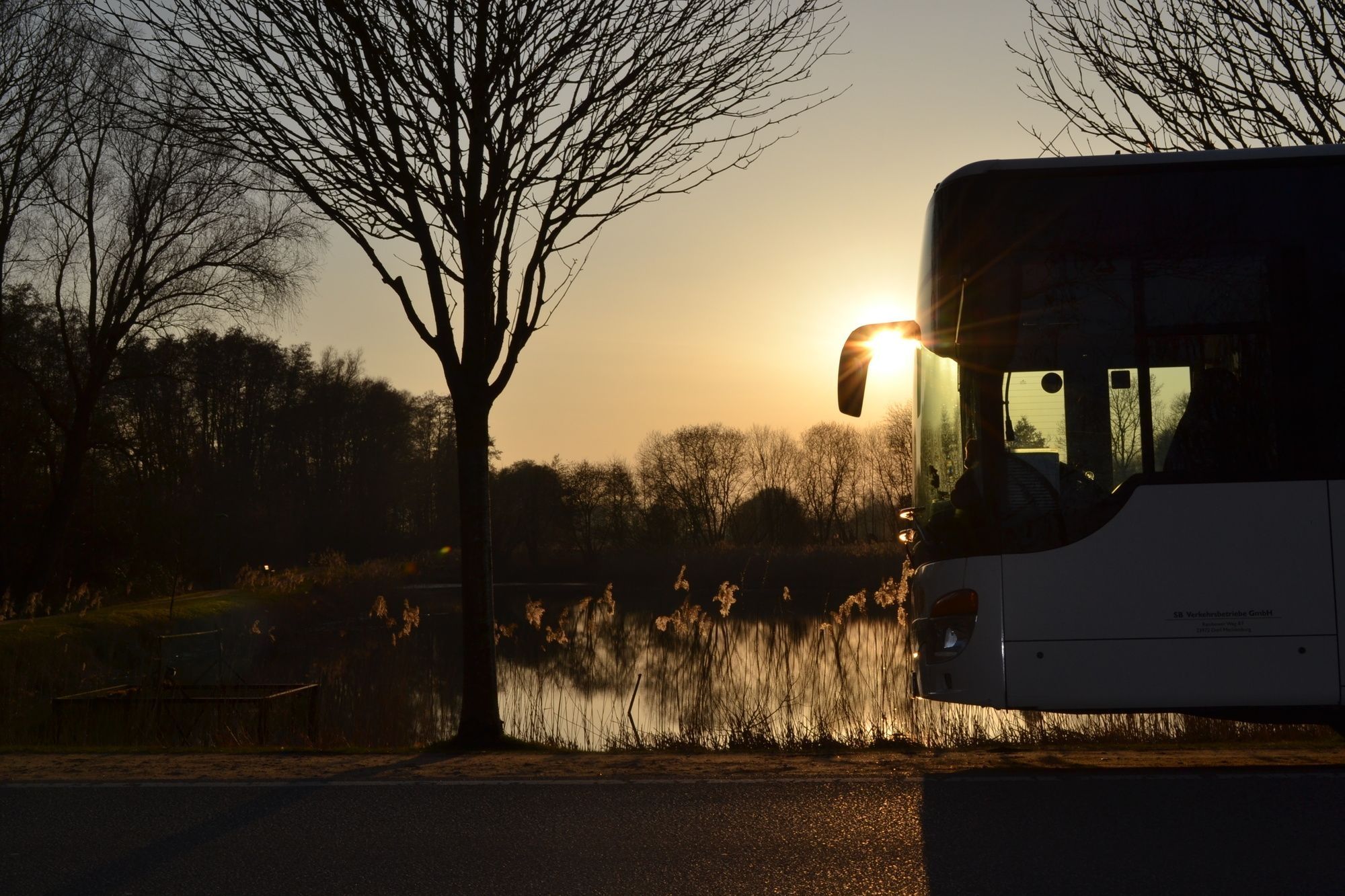 Landschaft, in der ein Bus von rechts ins Bild fährt
