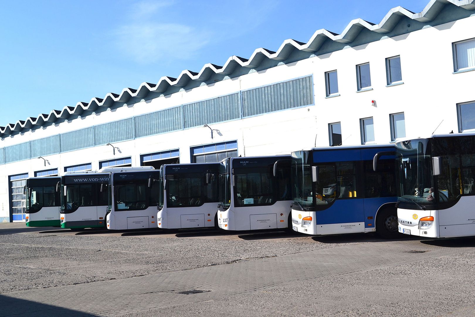 Parkende Busse in einer Reihe auf einem Parkplatz.