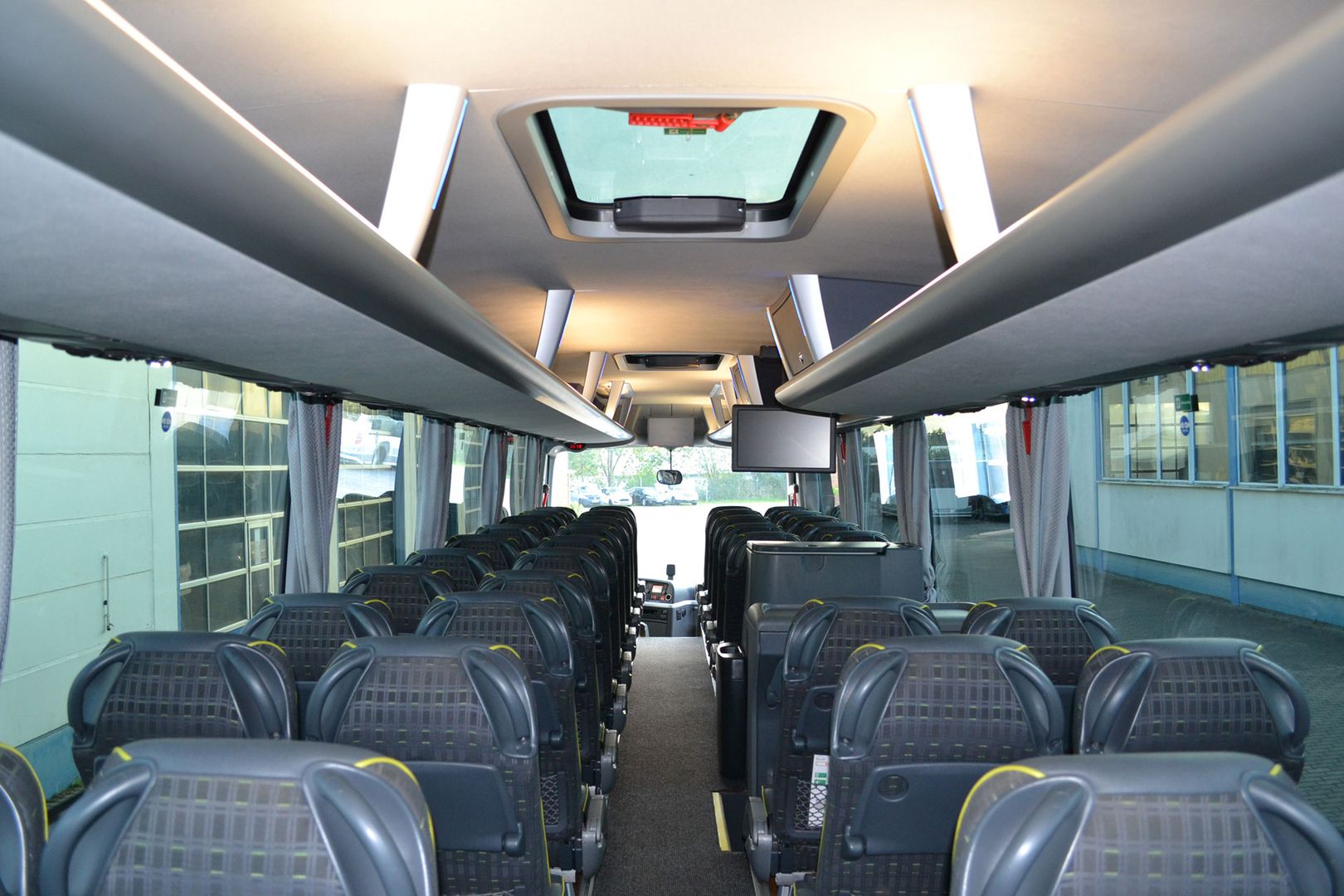 Innenansicht eines Busses mit zahlreichen Sitzen und einem großen Oberlicht für zusätzliches Licht.
